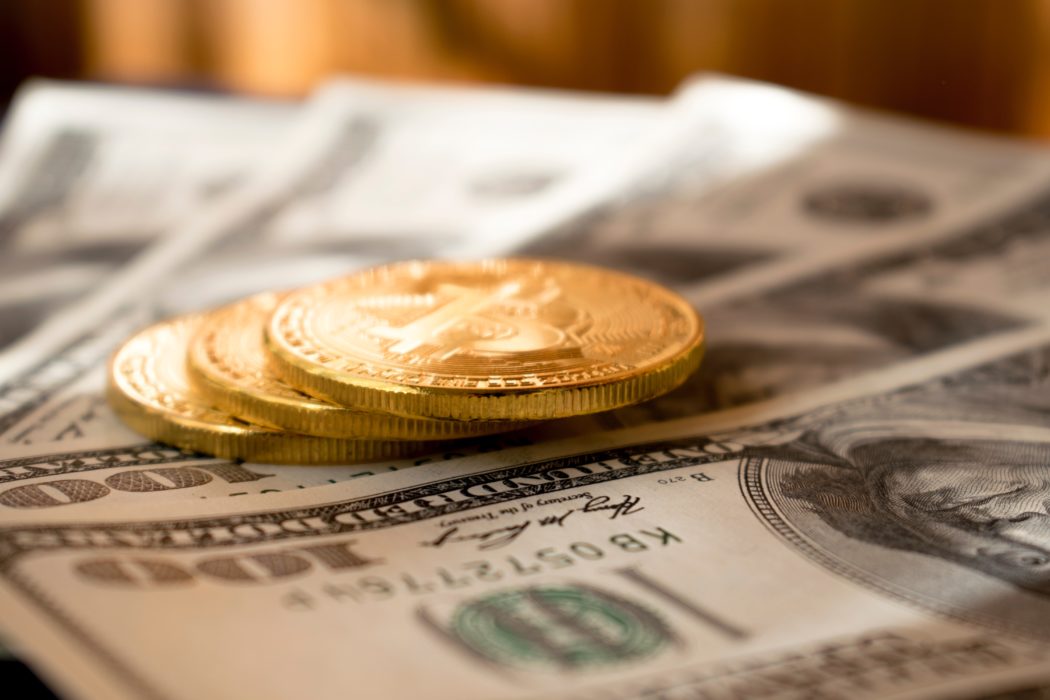 фотография монетки биткойна лежат на долларовых банкнотах